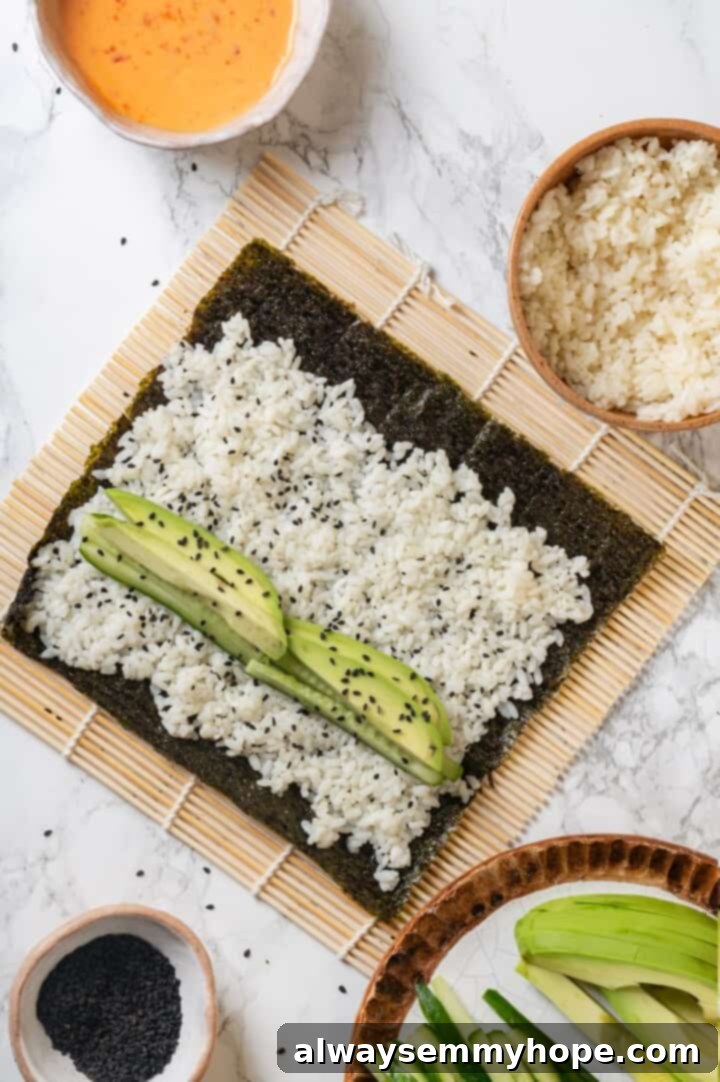 Overhead view of sushi rice, cucumber, and avocado on sheet of nori