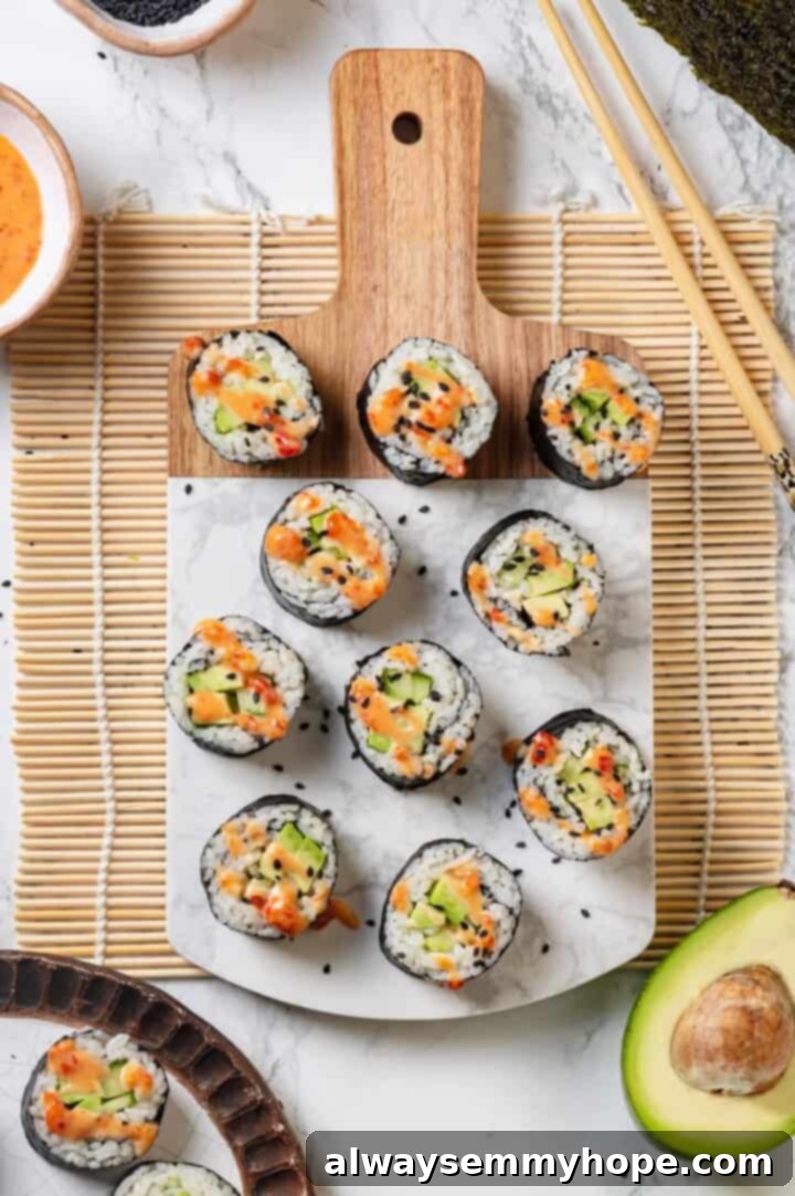 Overhead view of vegan avocado sushi on marble and wood serving board