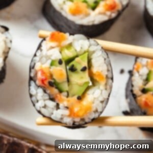 Chopsticks holding avocado sushi roll with bang bang sauce