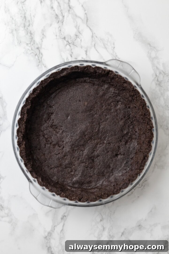 With an Oreo crust, decadent vegan mousse filling, and coconut whipped cream, this chocolate mousse pie recipe is absolutely irresistible! Overhead view of Oreo crumb mixture pressed evenly into a glass pie plate