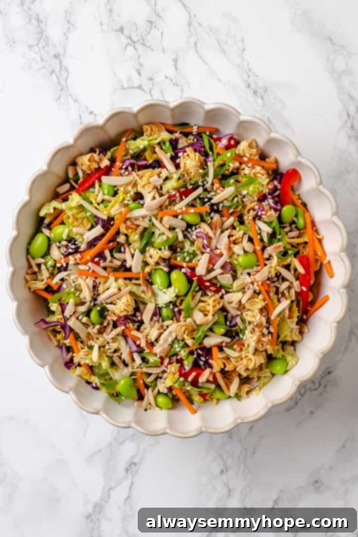 With crunchy noodles, almonds, cabbage and tender edamame in a zippy ginger dressing, this ramen noodle salad recipe is easy and delicious! Overhead view of ramen noodle salad in mixing bowl