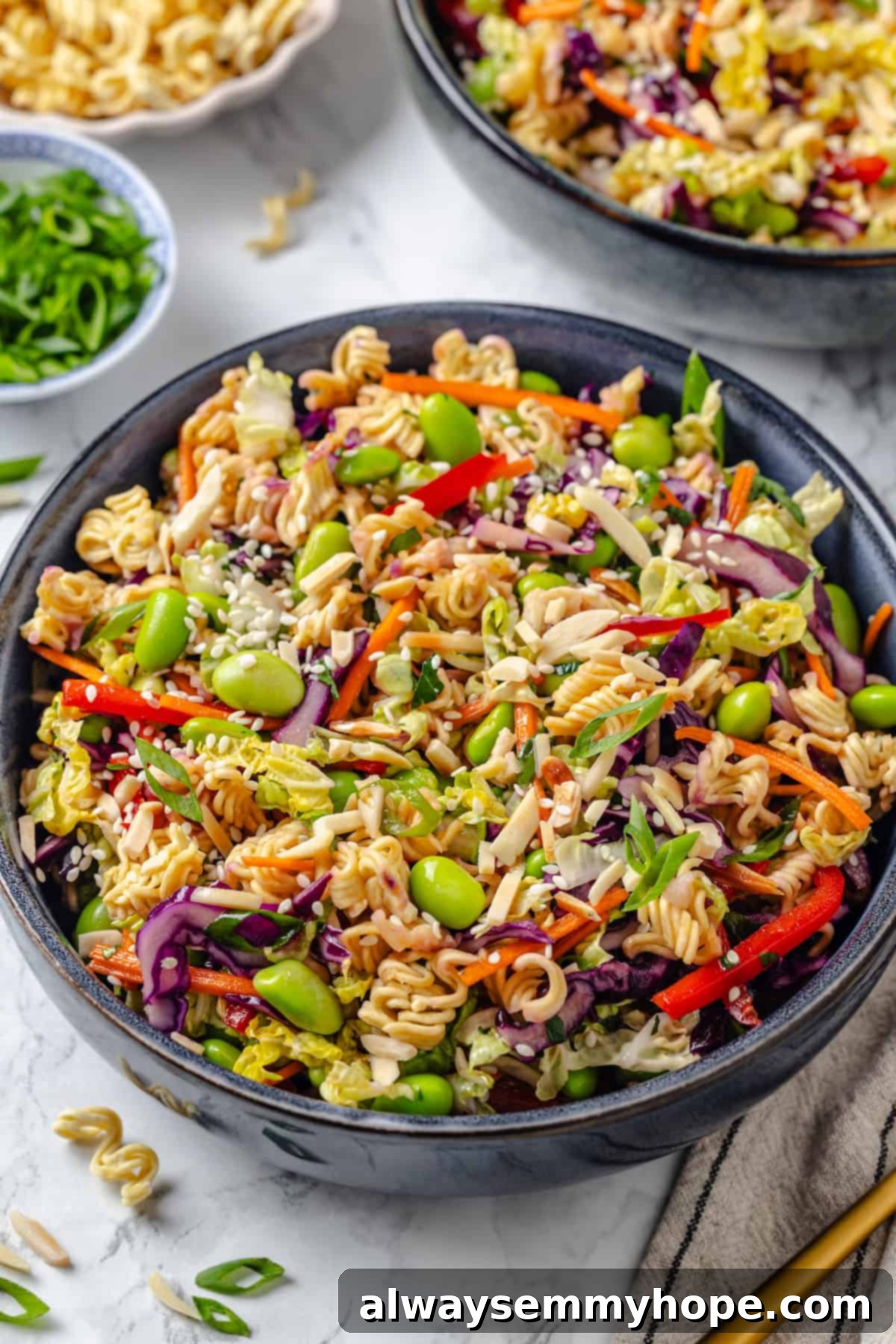 Overhead close-up view of a serving bowl filled with vegan ramen noodle salad, showing off the crunchy noodles, colorful vegetables, and zesty dressing
