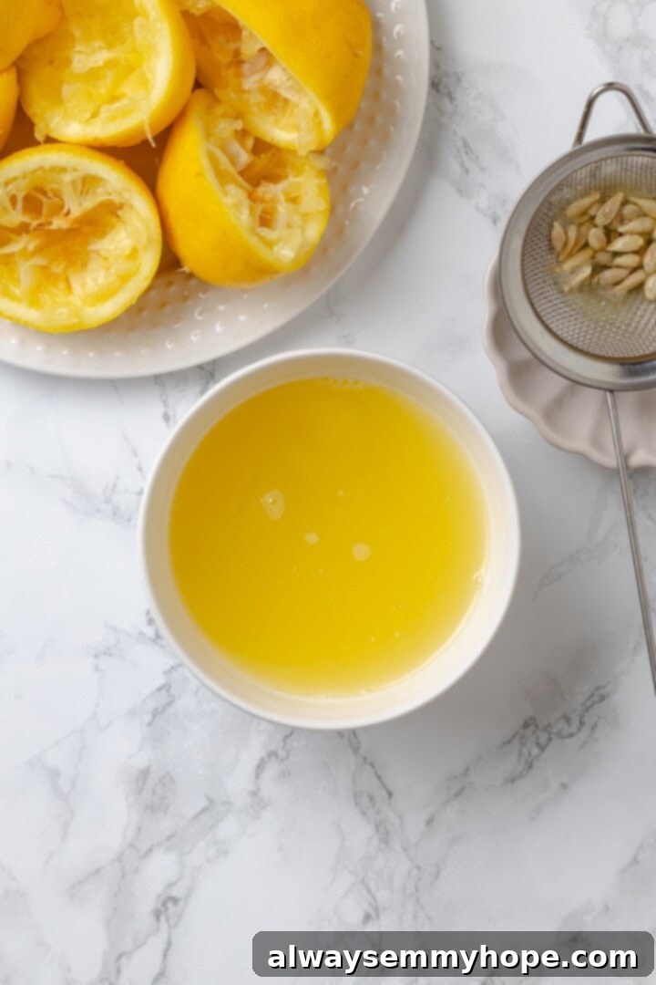 Overhead view of freshly squeezed lemon juice in a bowl next to juiced lemon halves