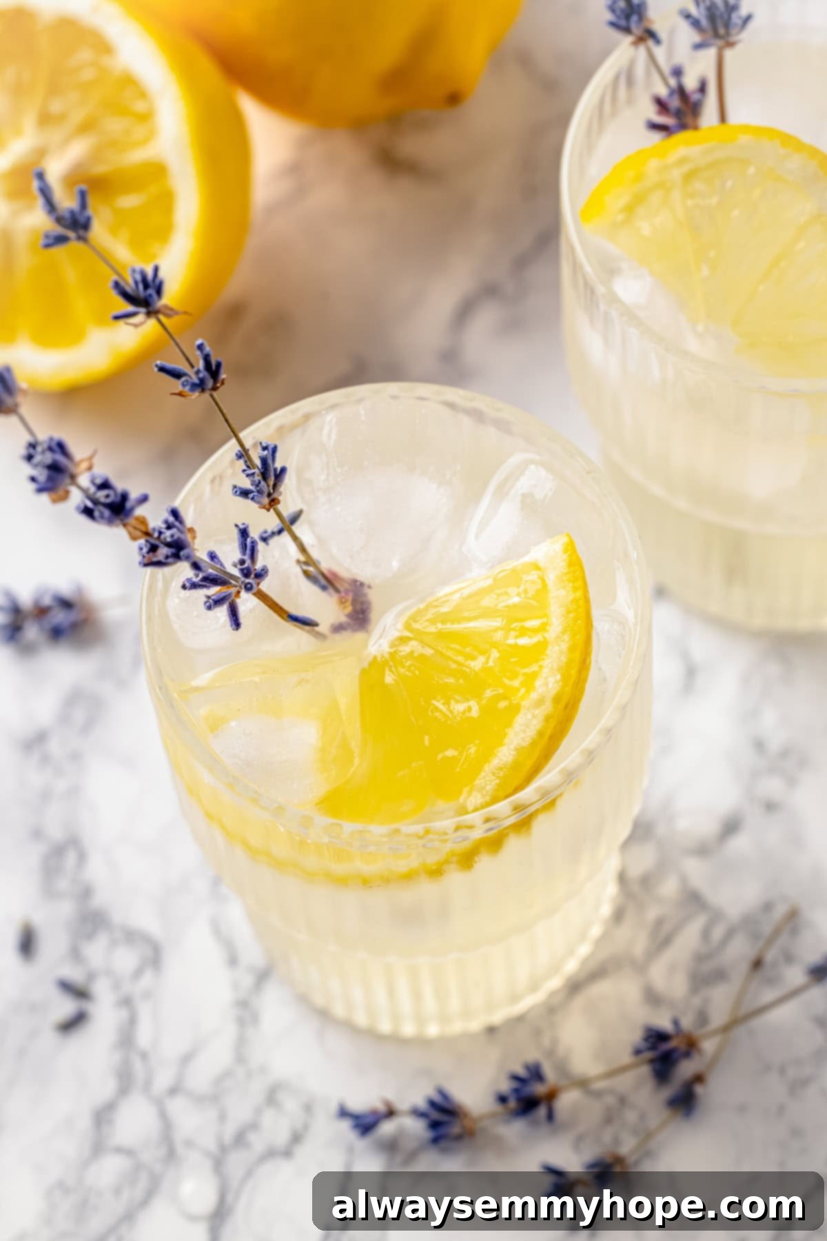 Top-down view of lavender lemonade in glasses with lemon and lavender garnishes, ready to serve