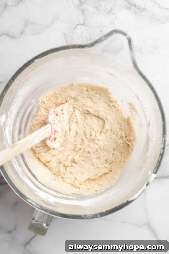Overhead view of vegan ladyfinger batter in glass mixing bowl with rubber spatula