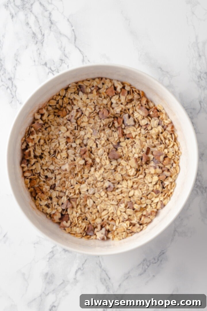 This baked oatmeal recipe is an easy meal prep breakfast! It's hearty and wholesome, with juicy berries and crunchy walnuts in every bite. Overhead view of oats, walnuts, baking powder, cinnamon, and salt mixed in a large bowl for baked oatmeal