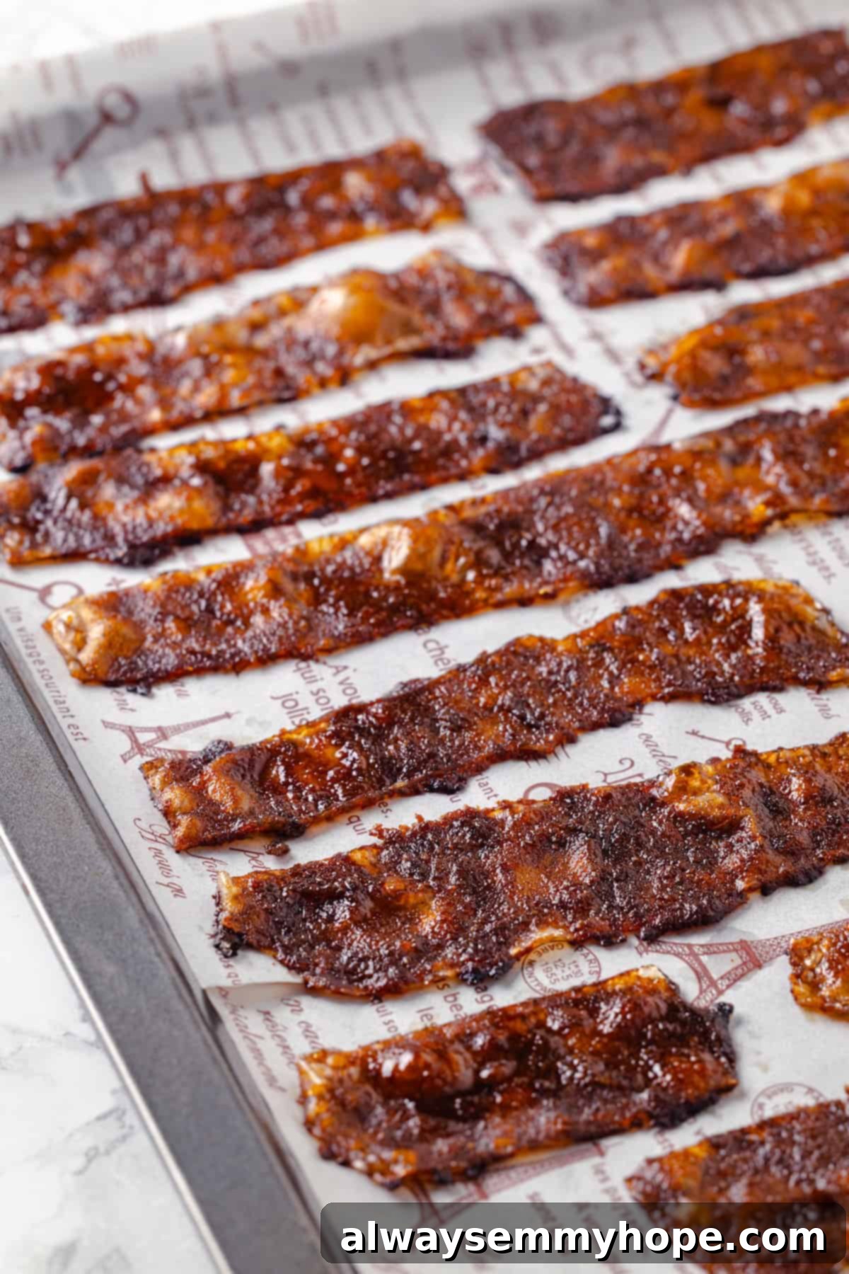 Rice paper is the secret for ultra crispy vegan bacon! This recipe is smoky, sweet, and savoury, and it's incredibly easy to make too. Crispy vegan bacon on parchment-lined baking sheet