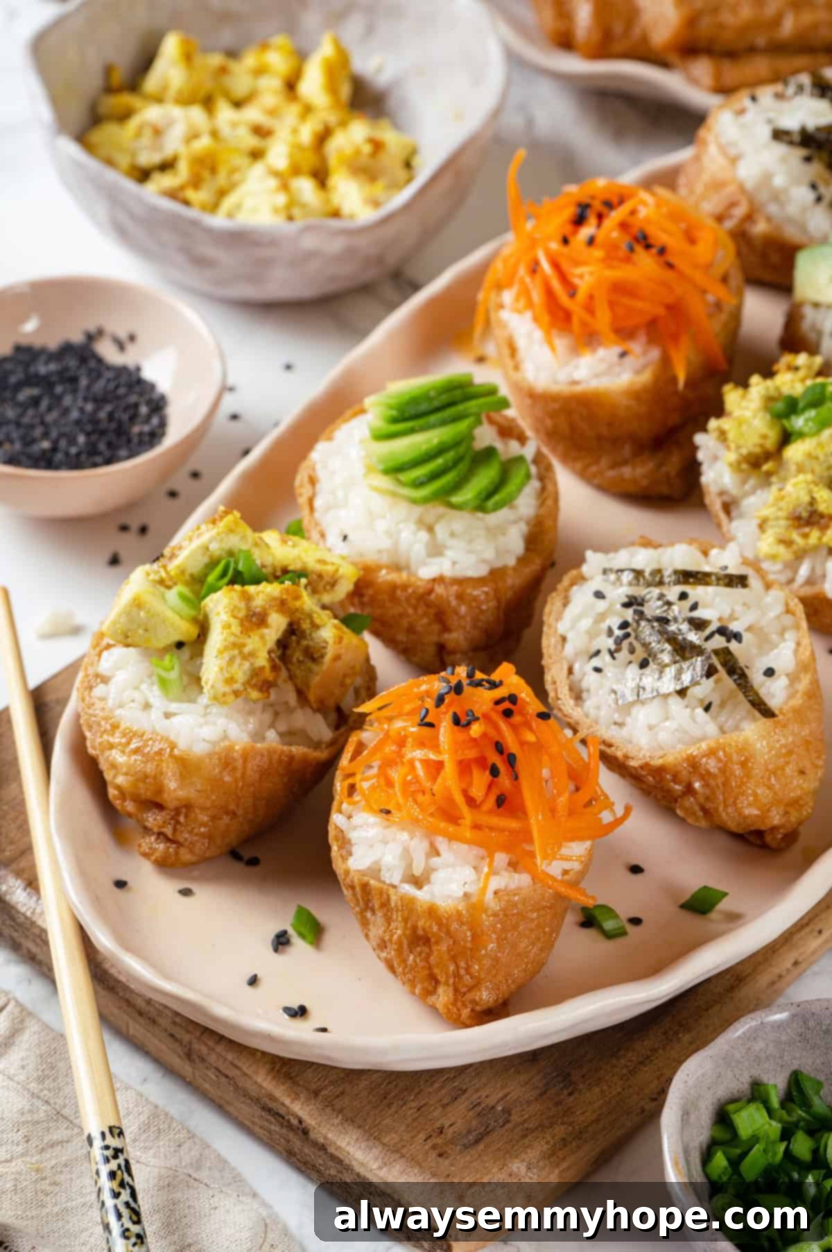 This inari sushi recipe tucks tangy sushi rice into tofu pockets with toppings like avocado, spicy carrots, and tofu scramble. Easy and fun! Vegan inari sushi topped with tofu, avocado, carrots, and nori