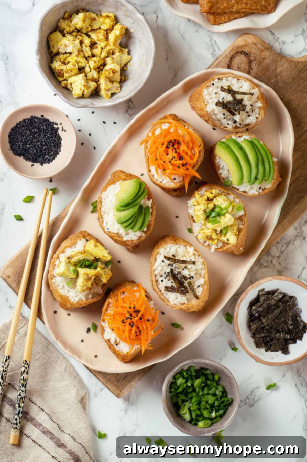 This inari sushi recipe tucks tangy sushi rice into tofu pockets with toppings like avocado, spicy carrots, and tofu scramble. Easy and fun! Overhead view of vegan inari sushi on platter with various toppings