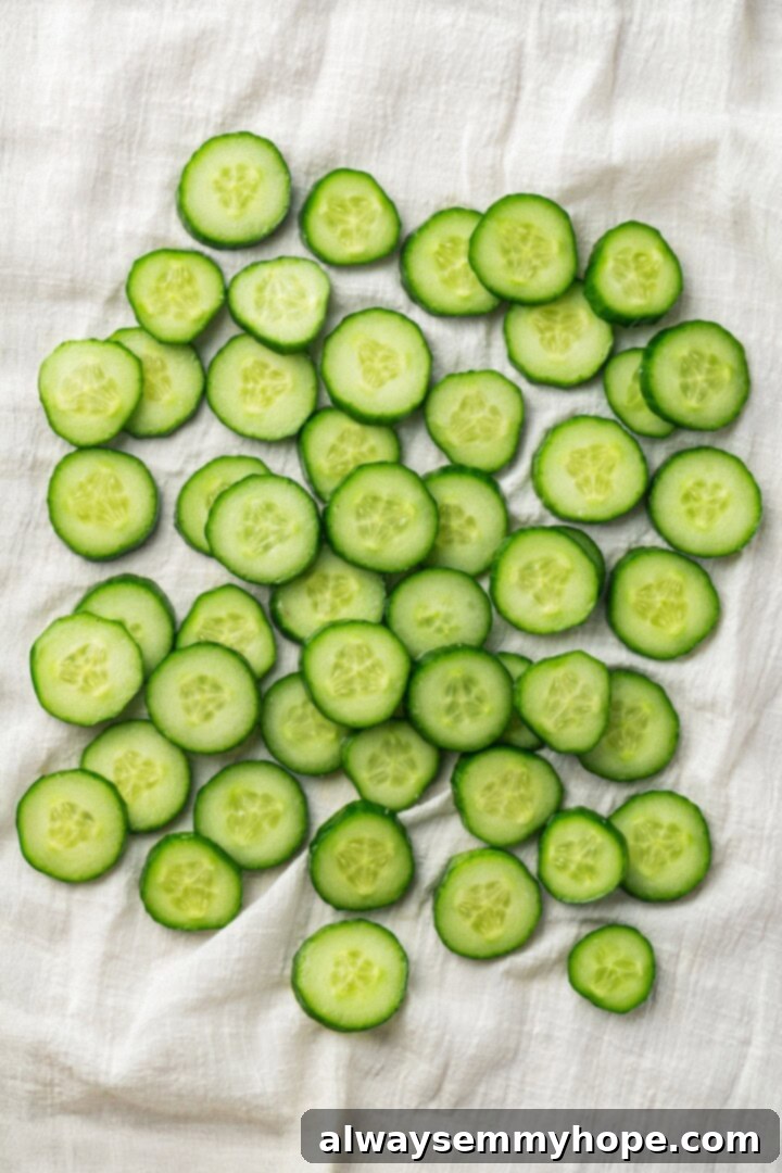 Crisp, refreshing, and full of bold flavour, this spicy Korean cucumber salad recipe is an easy side dish you’ll make all summer long! Overhead view of cucumber slices on a clean kitchen towel, being patted dry