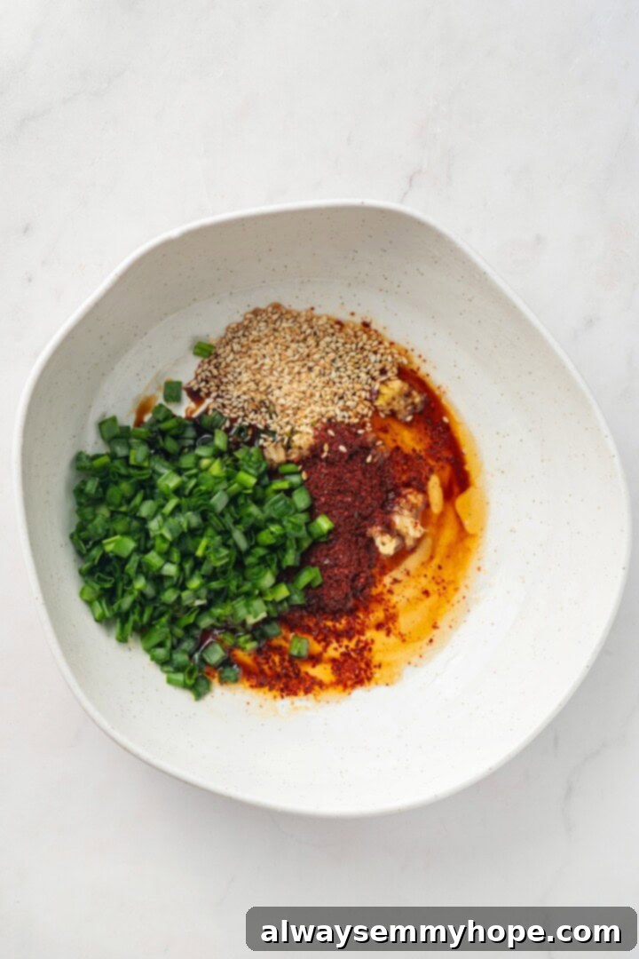 Crisp, refreshing, and full of bold flavour, this spicy Korean cucumber salad recipe is an easy side dish you’ll make all summer long! Overhead view of ingredients for Korean cucumber salad dressing in a bowl before stirring, vibrant colors of gochugaru visible