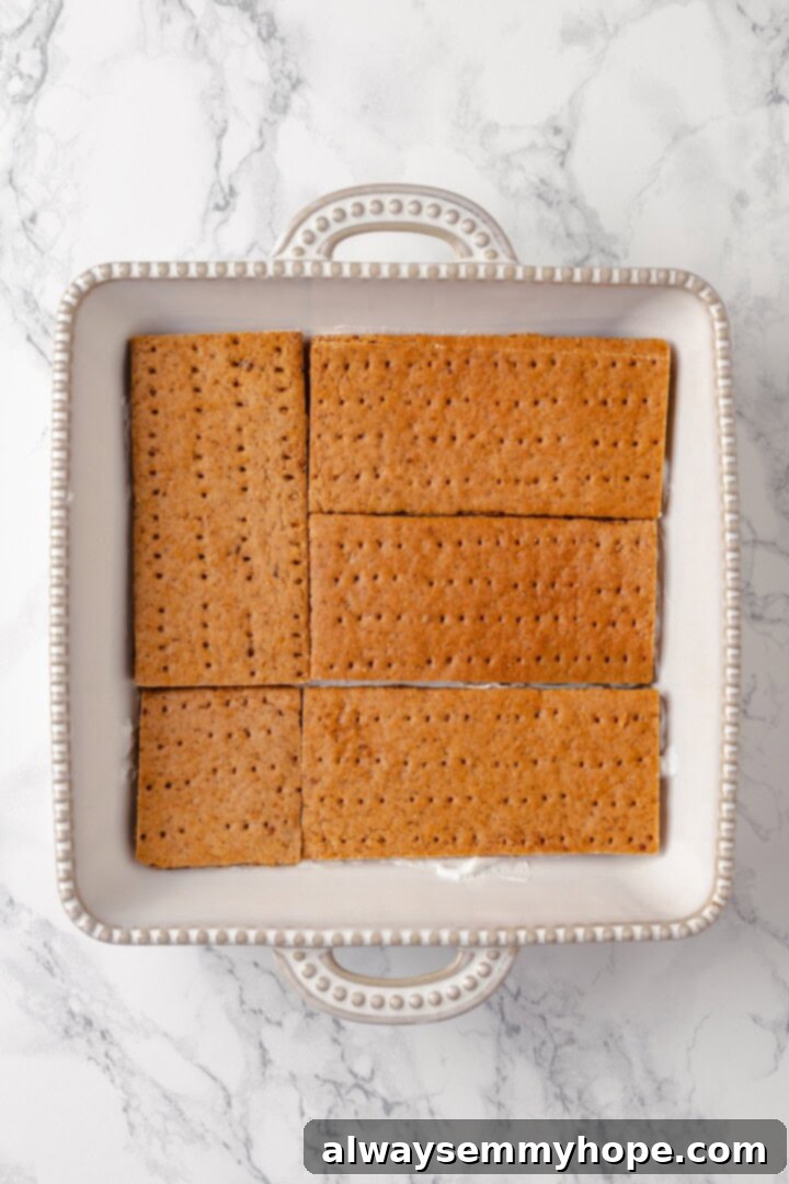 This strawberry icebox cake is cool, creamy, and super easy to make, with vegan whipped cream, fresh strawberries, and graham crackers. Yum! Graham crackers layered in dish for icebox cake