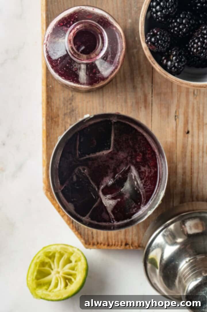 This summery blackberry margarita recipe is refreshing, delicious, and perfect for adding to your Taco Tuesday menu. It's always a hit! Overhead view of all blackberry margarita ingredients, including fresh berries, tequila, and lime, being added to a cocktail shaker with ice.