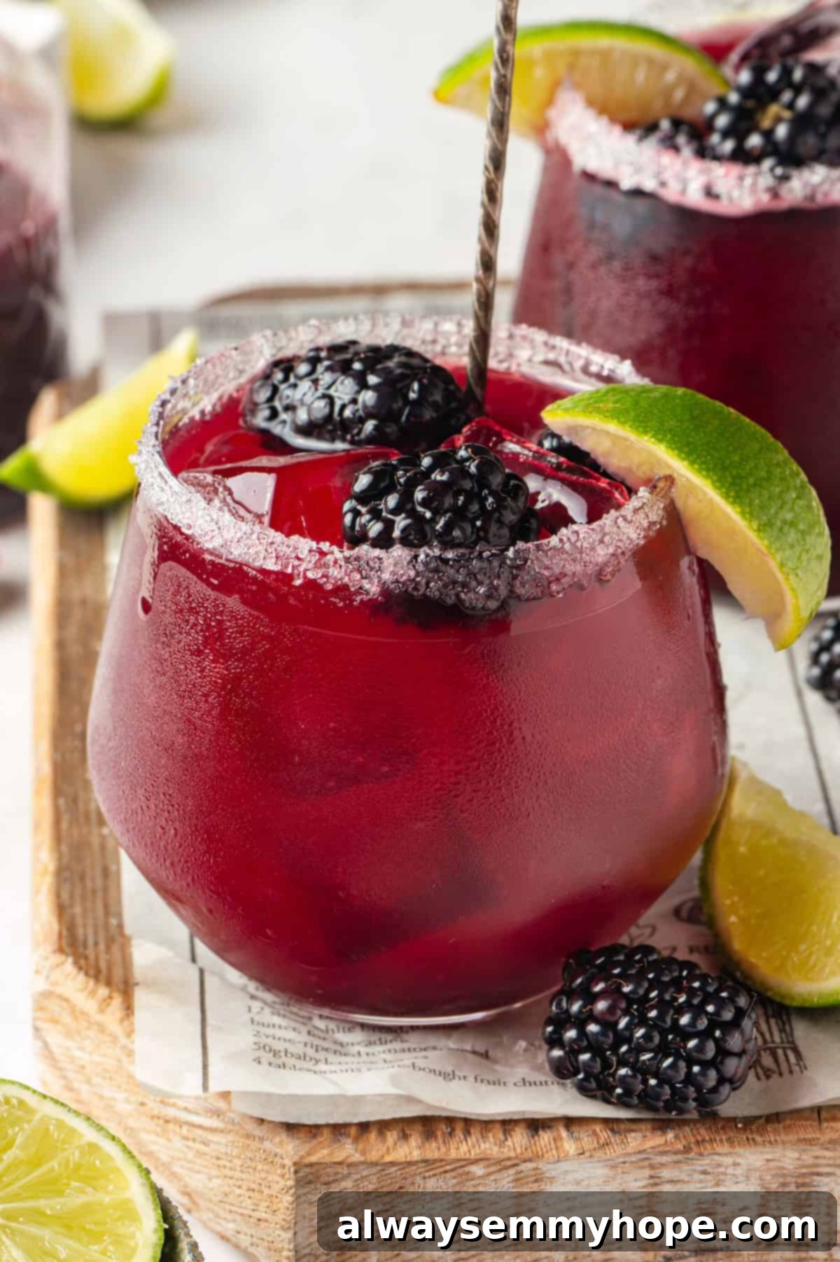 This summery blackberry margarita recipe is refreshing, delicious, and perfect for adding to your Taco Tuesday menu. It's always a hit! Homemade blackberry margarita in a short glass, garnished with fresh blackberries and a lime wedge, sitting on a wooden surface.