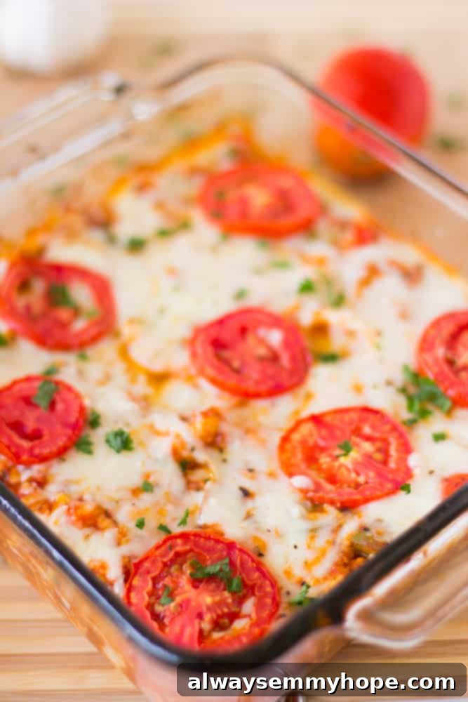 Cheesy Cauliflower Pizza Bake 2 Overhead shot of a golden-brown, bubbly cauliflower pizza casserole in a clear glass baking dish, garnished with fresh herbs.
