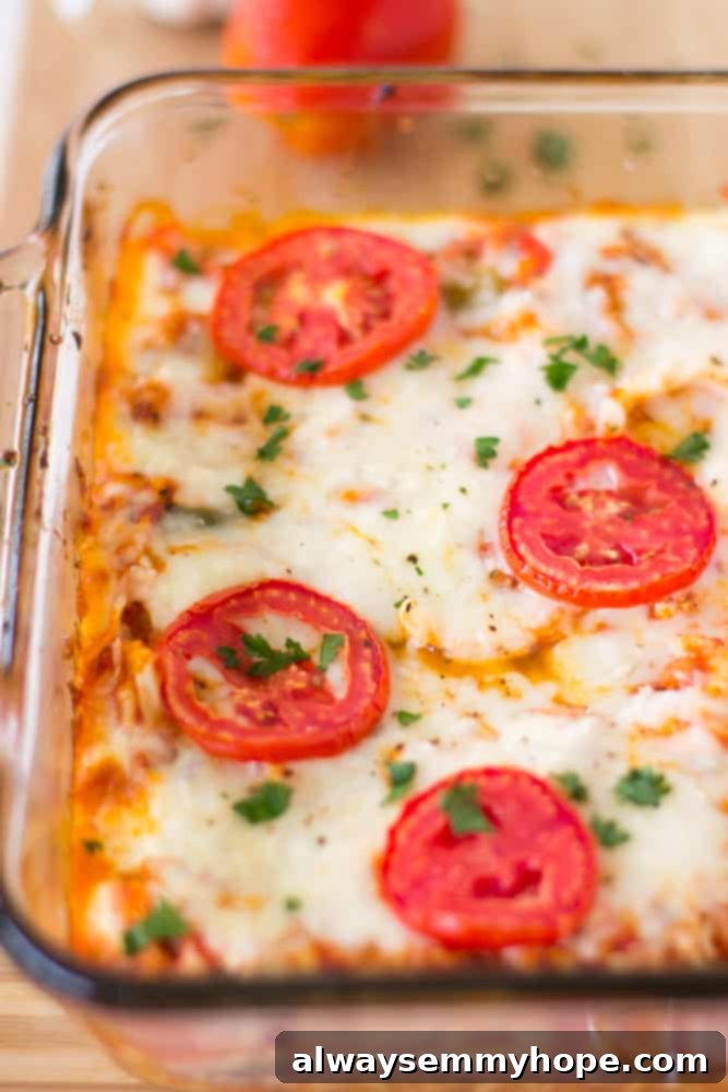 Cheesy Cauliflower Pizza Bake 3 Close-up shot revealing the cheesy, saucy layers of the cauliflower pizza casserole in a glass baking dish, showing melted cheese and visible cauliflower florets.