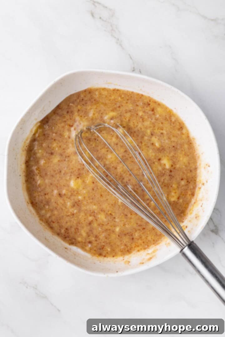 Overhead view of wet ingredients in mixing bowl with whisk