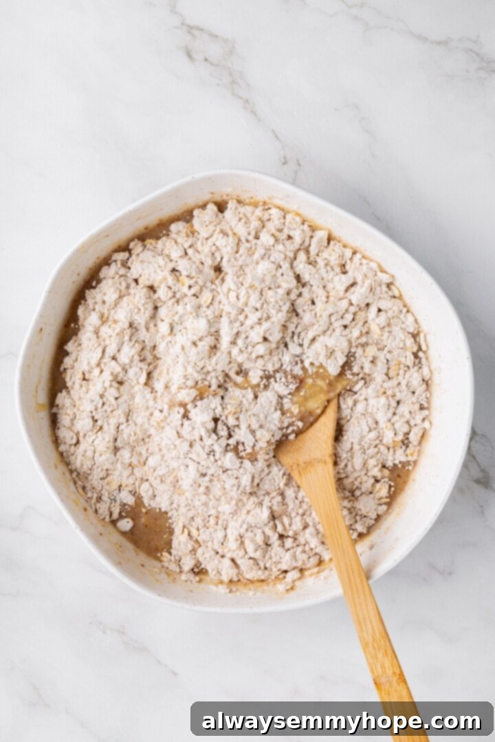 Overhead view of dry ingredients added to wet ingredients in mixing bowl