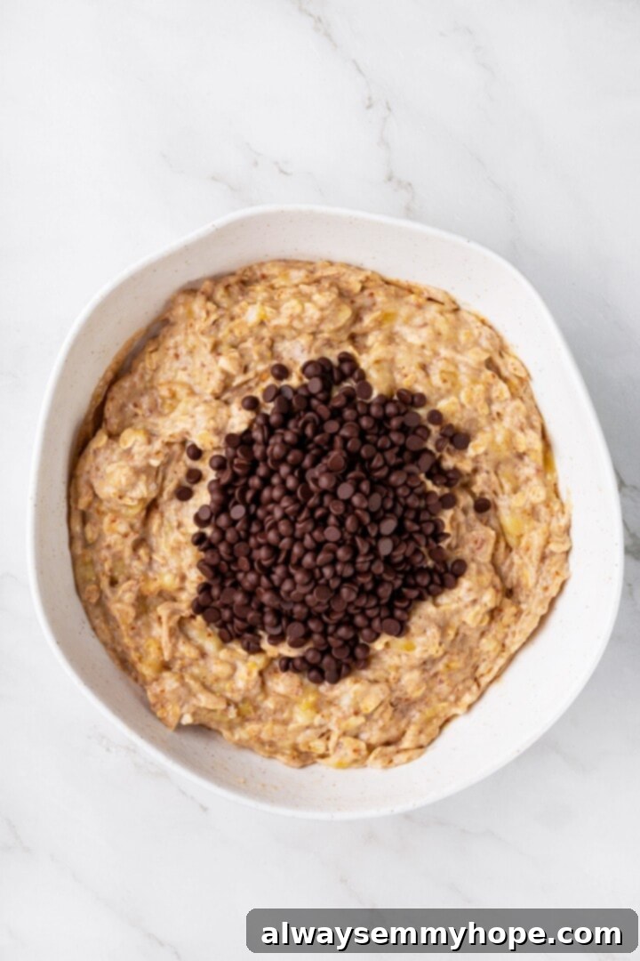 Overhead view of chocolate chips added to bowl of batter