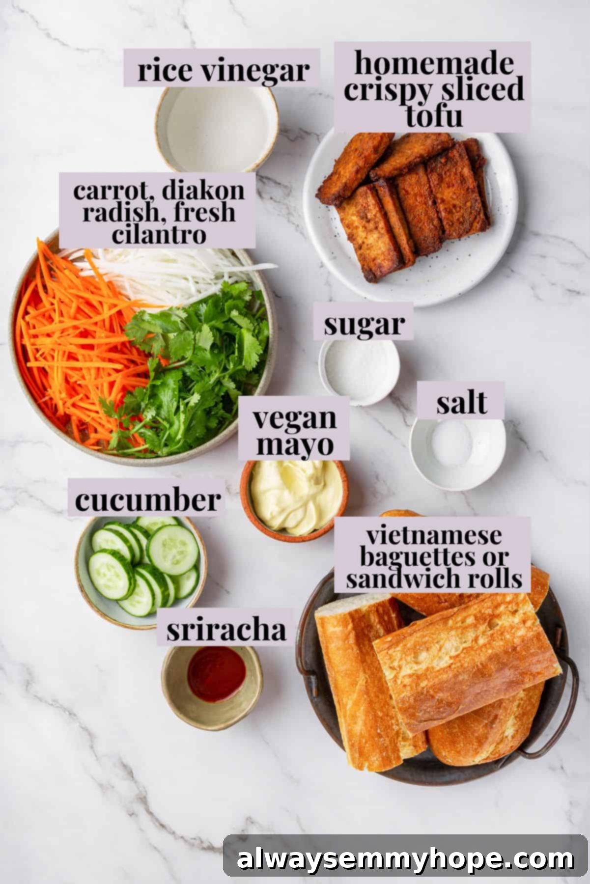 Crispy air fried tofu is layered with crunchy pickled veggies on crusty baguette to make this fresh and flavourful vegan Tofu Banh Mi recipe! Overhead view of all ingredients for tofu banh mi, including pickled veggies, baguette, and mayo