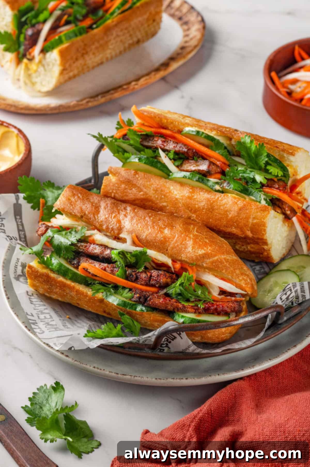Crispy air fried tofu is layered with crunchy pickled veggies on crusty baguette to make this fresh and flavourful vegan Tofu Banh Mi recipe! Two perfectly arranged vegan tofu banh mi sandwiches, showcasing the vibrant fillings and crispy bread