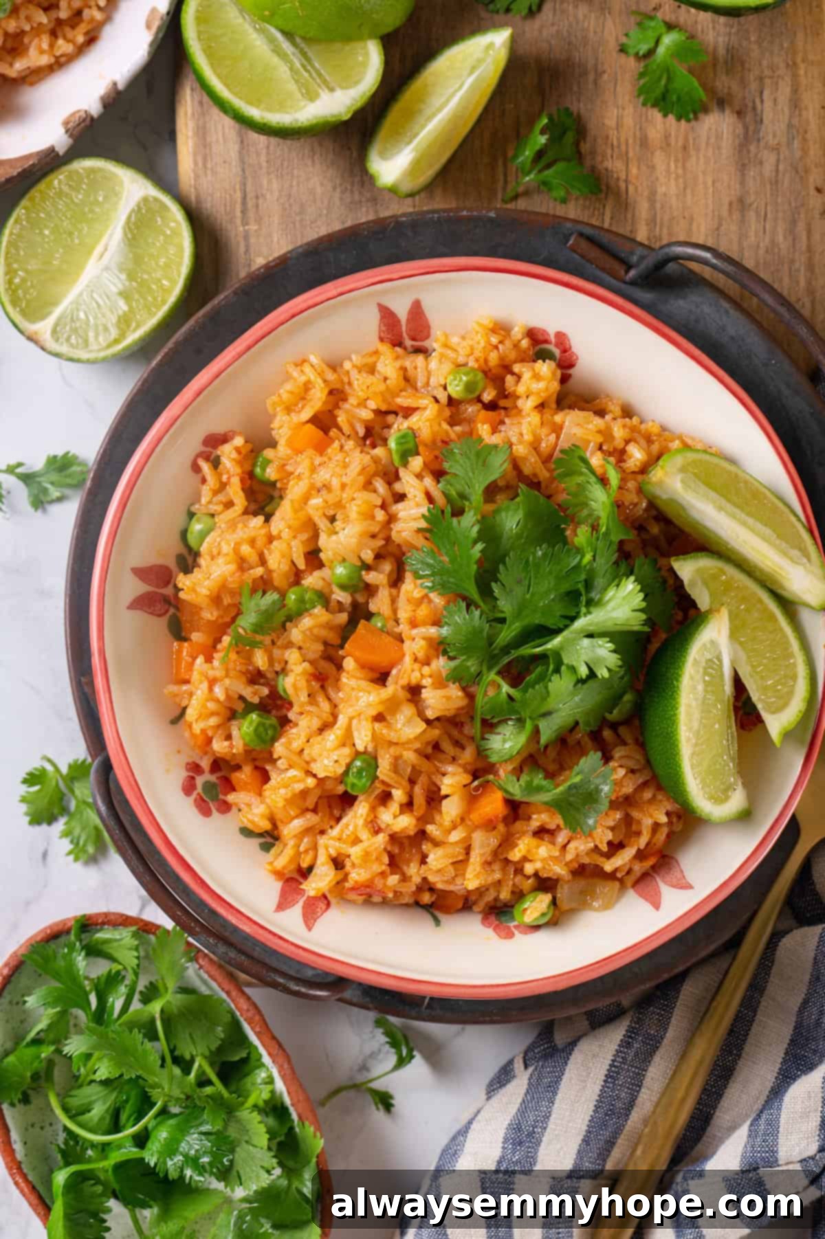 Instant Pot Mexican Rice is a total game-changer! It turns out perfectly cooked and fluffy every time. This easy recipe will be your go-to! Overhead view of Instant Pot Mexican rice in bowl with cilantro and lime wedges