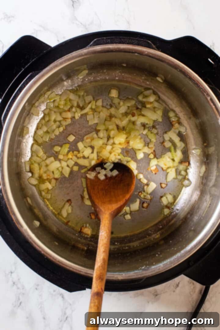 Instant Pot Mexican Rice is a total game-changer! It turns out perfectly cooked and fluffy every time. This easy recipe will be your go-to! Overhead view of onion cooking in Instant Pot
