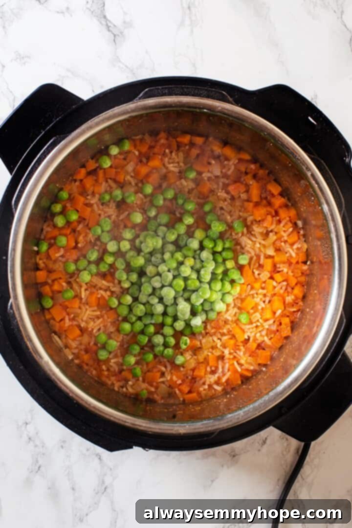 Instant Pot Mexican Rice is a total game-changer! It turns out perfectly cooked and fluffy every time. This easy recipe will be your go-to! Overhead view of frozen peas added to Instant Pot Mexican rice