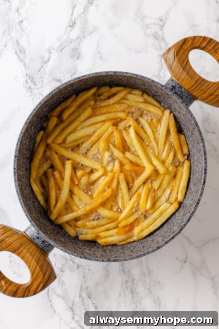 Whether you bake them or deep fry them, these crispy Garlic Fries are guaranteed to be a hit! They're cheesy, easy and packed with flavour. Overhead view of fries cooking in oil