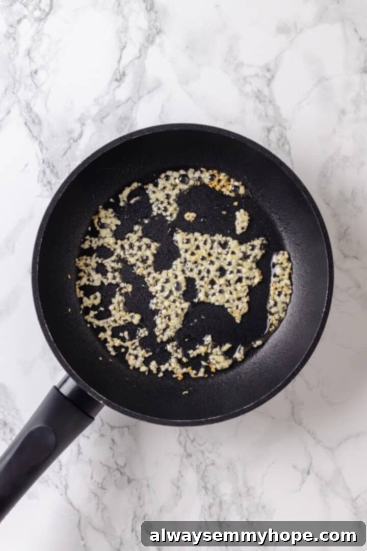 Whether you bake them or deep fry them, these crispy Garlic Fries are guaranteed to be a hit! They're cheesy, easy and packed with flavour. Overhead view of garlic and oil in skillet