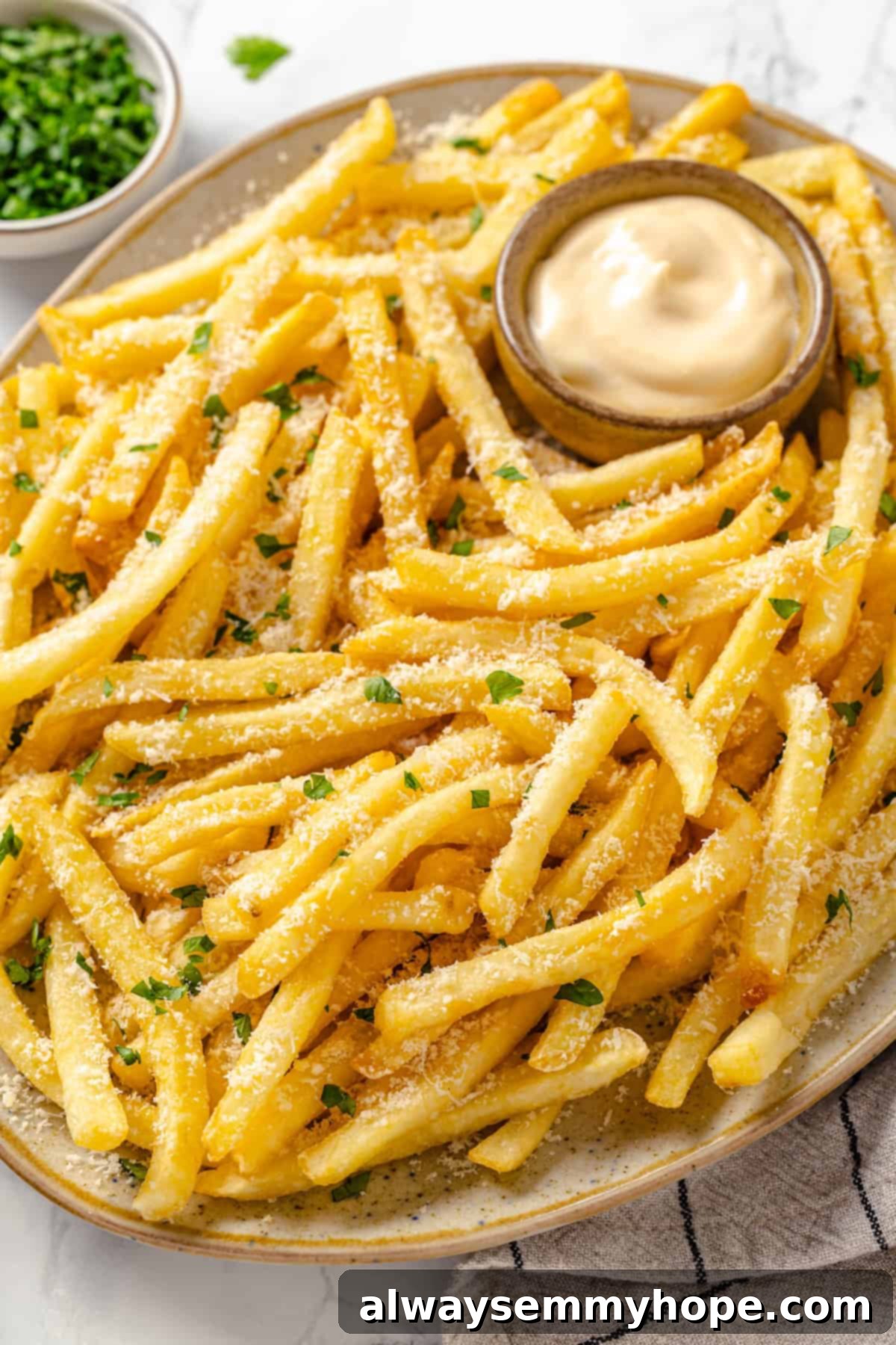 Whether you bake them or deep fry them, these crispy Garlic Fries are guaranteed to be a hit! They're cheesy, easy and packed with flavour. Platter of vegan garlic fries with aioli