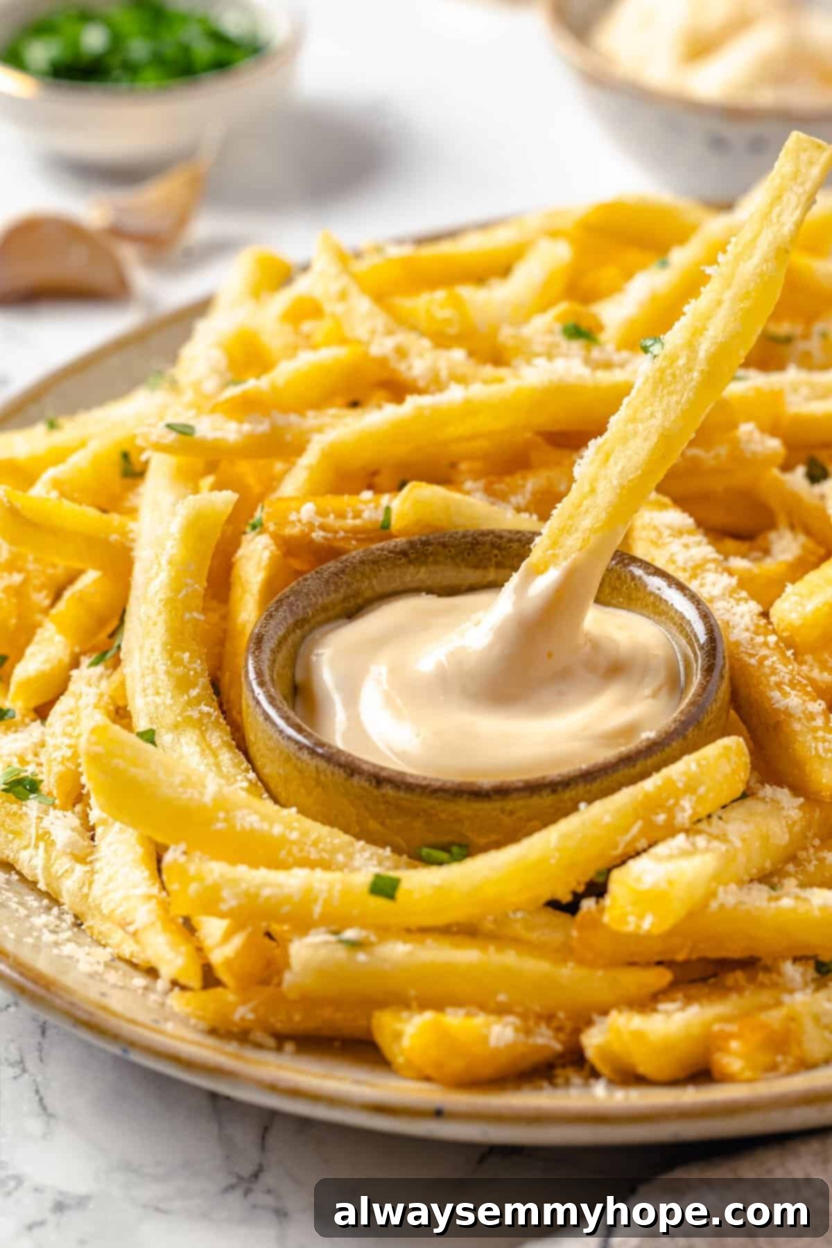 Whether you bake them or deep fry them, these crispy Garlic Fries are guaranteed to be a hit! They're cheesy, easy and packed with flavour. Dipping garlic fry into bowl of aioli