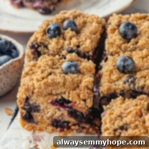 Grandma's Blueberry Buckle 2 Sliced blueberry buckle on parchment paper, showcasing the golden crust and berry-filled interior.