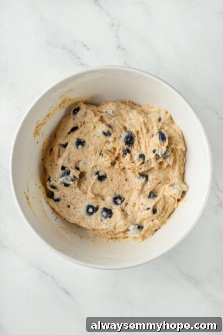A little bit like coffee cake, this Blueberry Buckle is loaded with berries, then topped with brown sugar cinnamon streusel. So delicious! Overhead view of blueberry buckle cake batter in a mixing bowl with fresh blueberries gently folded in.