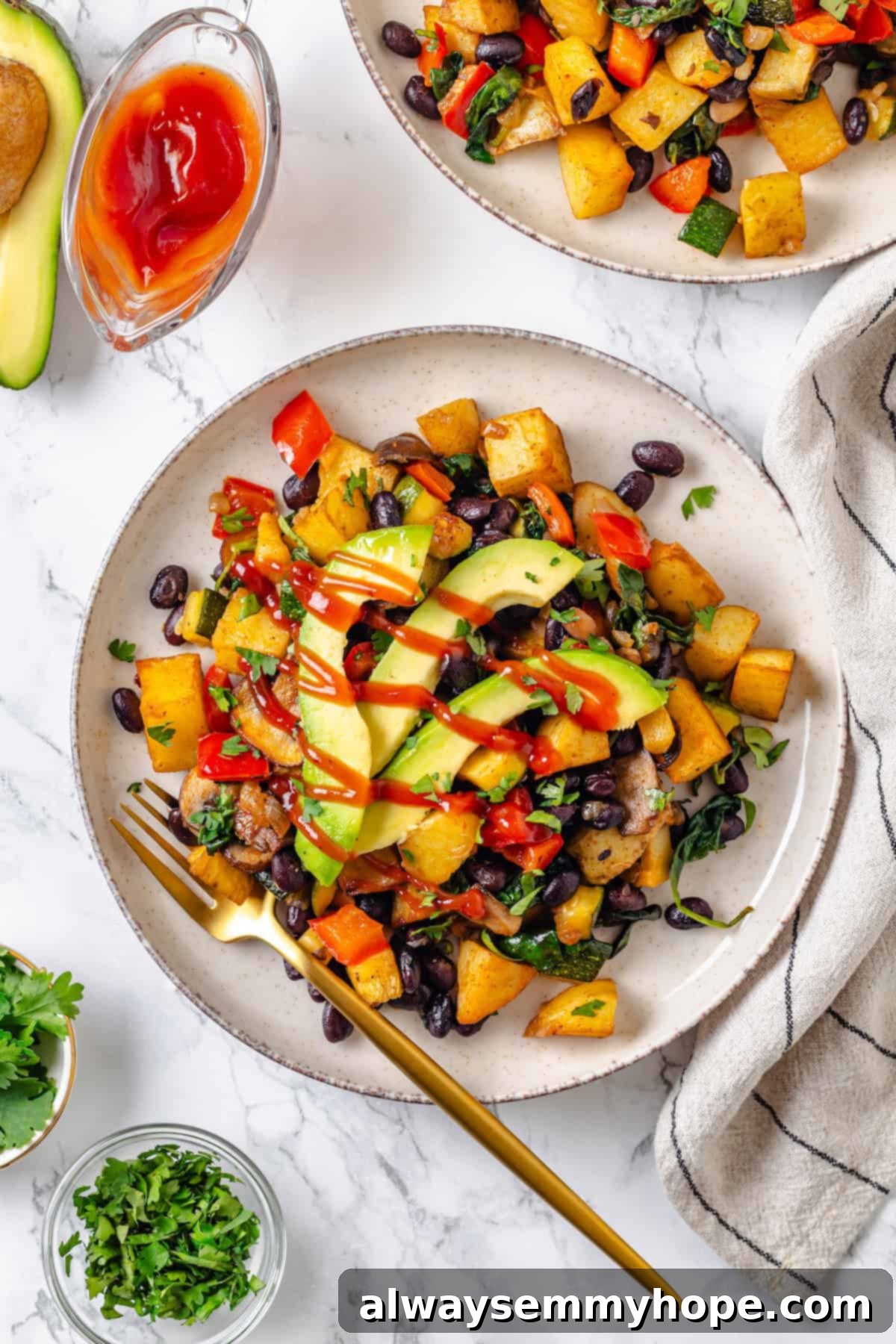 Overhead view of vegan breakfast hash on plate with fork, showing a vibrant mix of potatoes, beans, and colorful vegetables