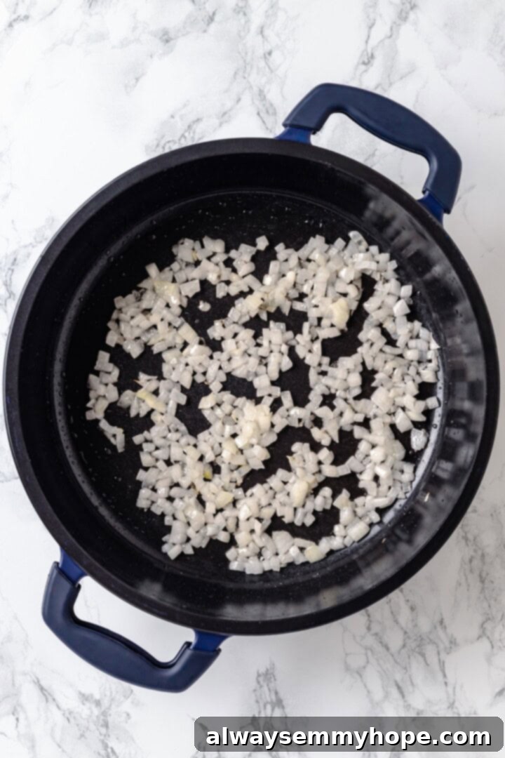 Overhead view of diced yellow onions sautéing in a skillet until translucent