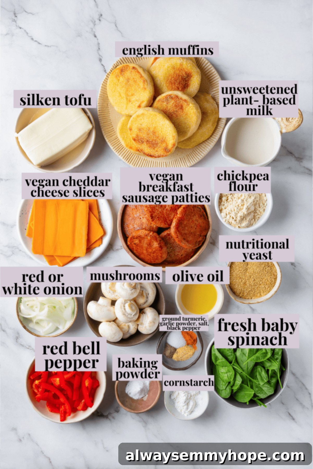 Overhead view of fresh ingredients for make-ahead vegan breakfast sandwiches, including tofu, vegetables, English muffins, sausage, and cheese