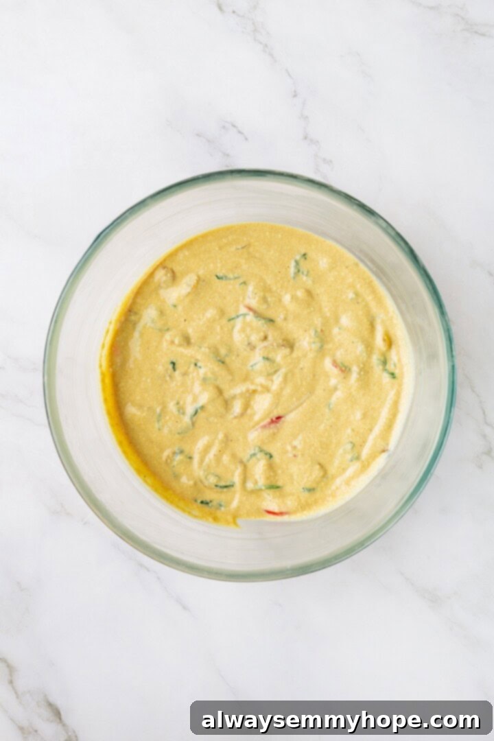 Overhead view of the tofu omelet mixture with sautéed vegetables folded in, ready for baking