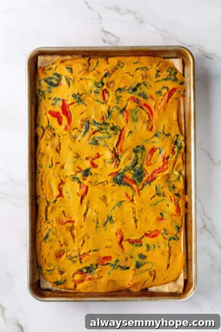 Overhead view of the vegan omelet spread evenly in a sheet pan, ready to bake until golden