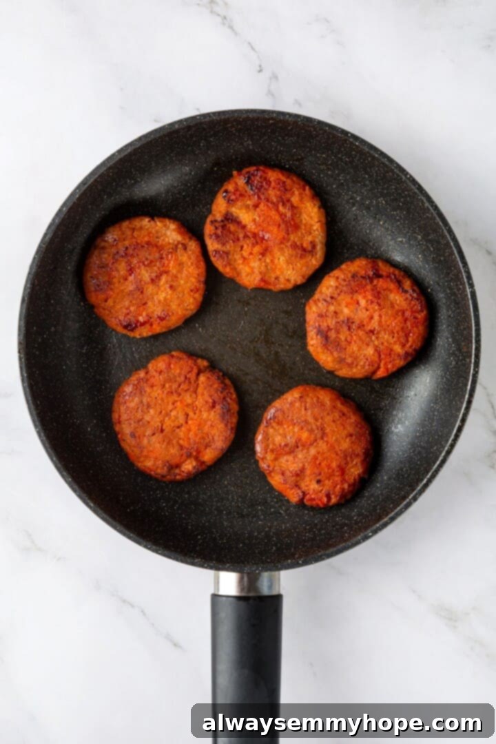Overhead view of perfectly cooked vegan sausage patties in a skillet, ready for assembly