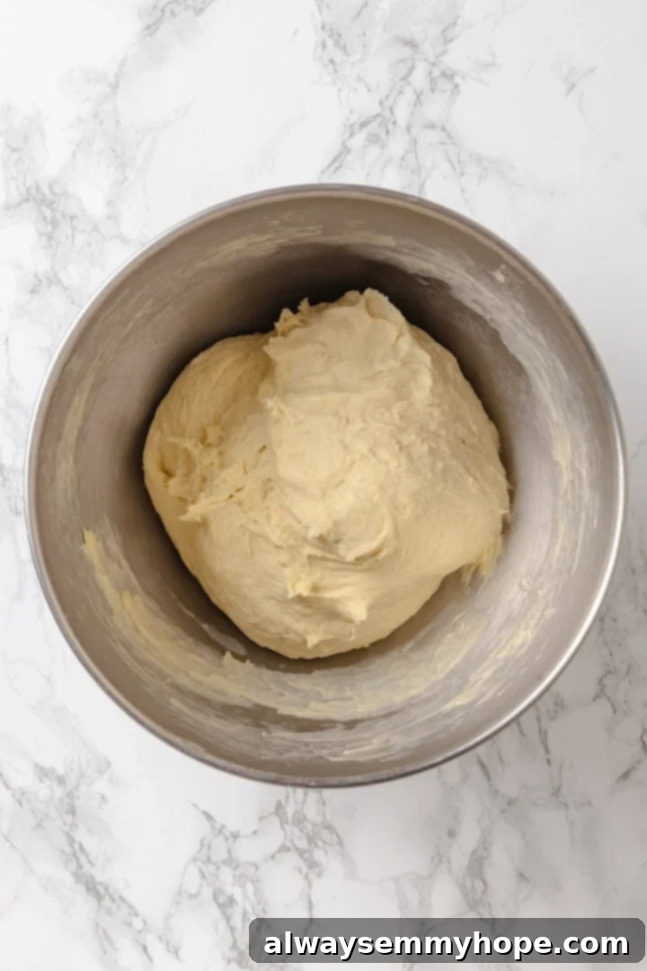 Knead the French bread dough until it's smooth and elastic, developing the gluten for a perfect texture. Overhead view of a perfectly kneaded French bread dough in a mixing bowl, smooth and elastic, ready for its first rise.