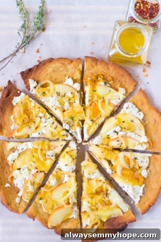 This Goat Cheese Pizza with Caramelized Onions and Apples is sprinkled with thyme, drizzled with honey and incredibly tasty! Delicious homemade goat cheese pizza with caramelized onions and sliced apples, garnished with fresh thyme and a honey drizzle on a white table, top-down view.