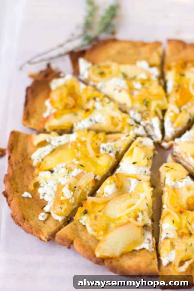 This Goat Cheese Pizza with Caramelized Onions and Apples is sprinkled with thyme, drizzled with honey and incredibly tasty! Side view of a freshly baked slice of goat cheese pizza, showcasing the layers of rich caramelized onions, tender apple slices, and creamy melted goat cheese on a perfectly golden, crispy crust.