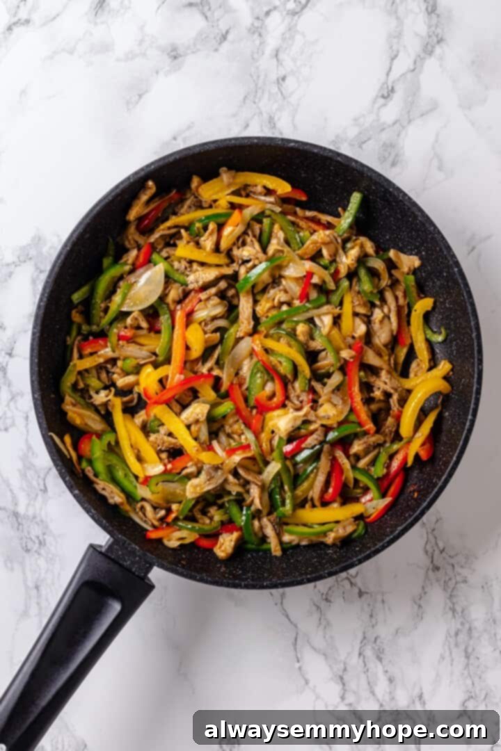 Sizzling mushroom fajitas, with colorful bell peppers and onions, actively cooking in a large skillet.