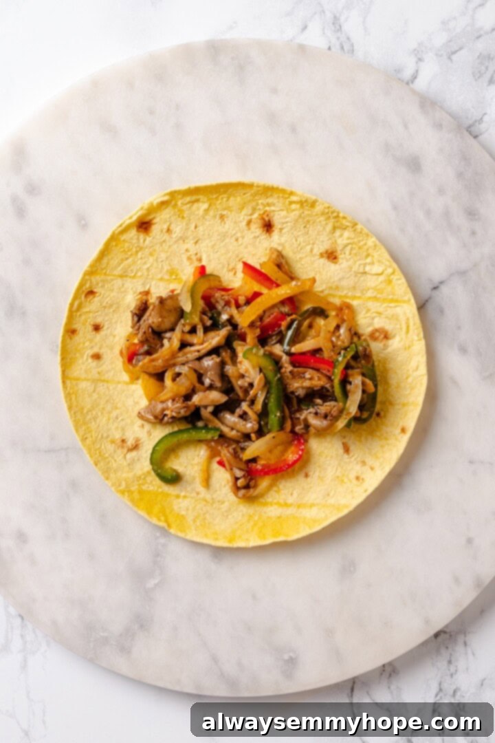 A warm tortilla being filled with a generous spoonful of the colorful and aromatic mushroom fajita mixture.