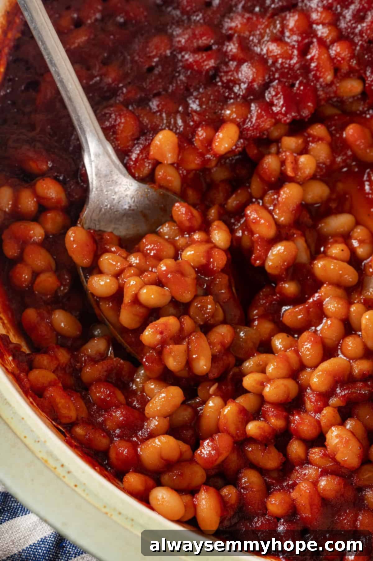 This vegan Baked Beans recipe has all the sweet, tangy, smoky flavour you love! Starting with canned beans makes this recipe a cinch. Spoonful of baked beans in pot