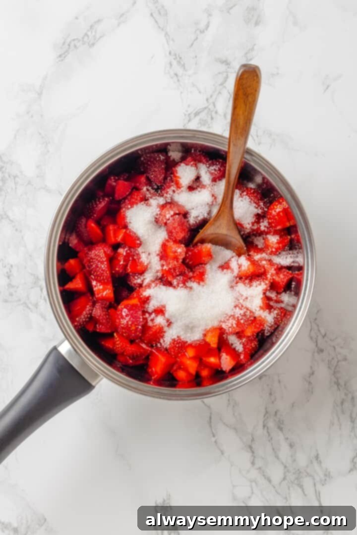 Spoon stirring sugar into chopped strawberries in a saucepan