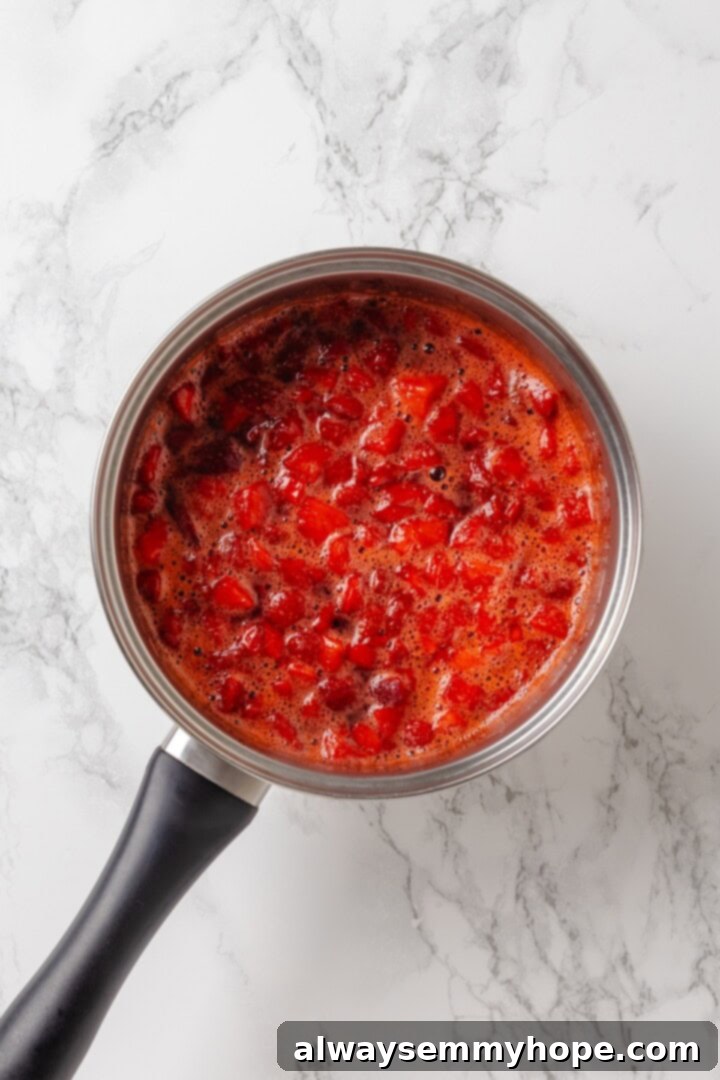 Overhead view of strawberry filling gently simmering in a pan after adding lemon juice