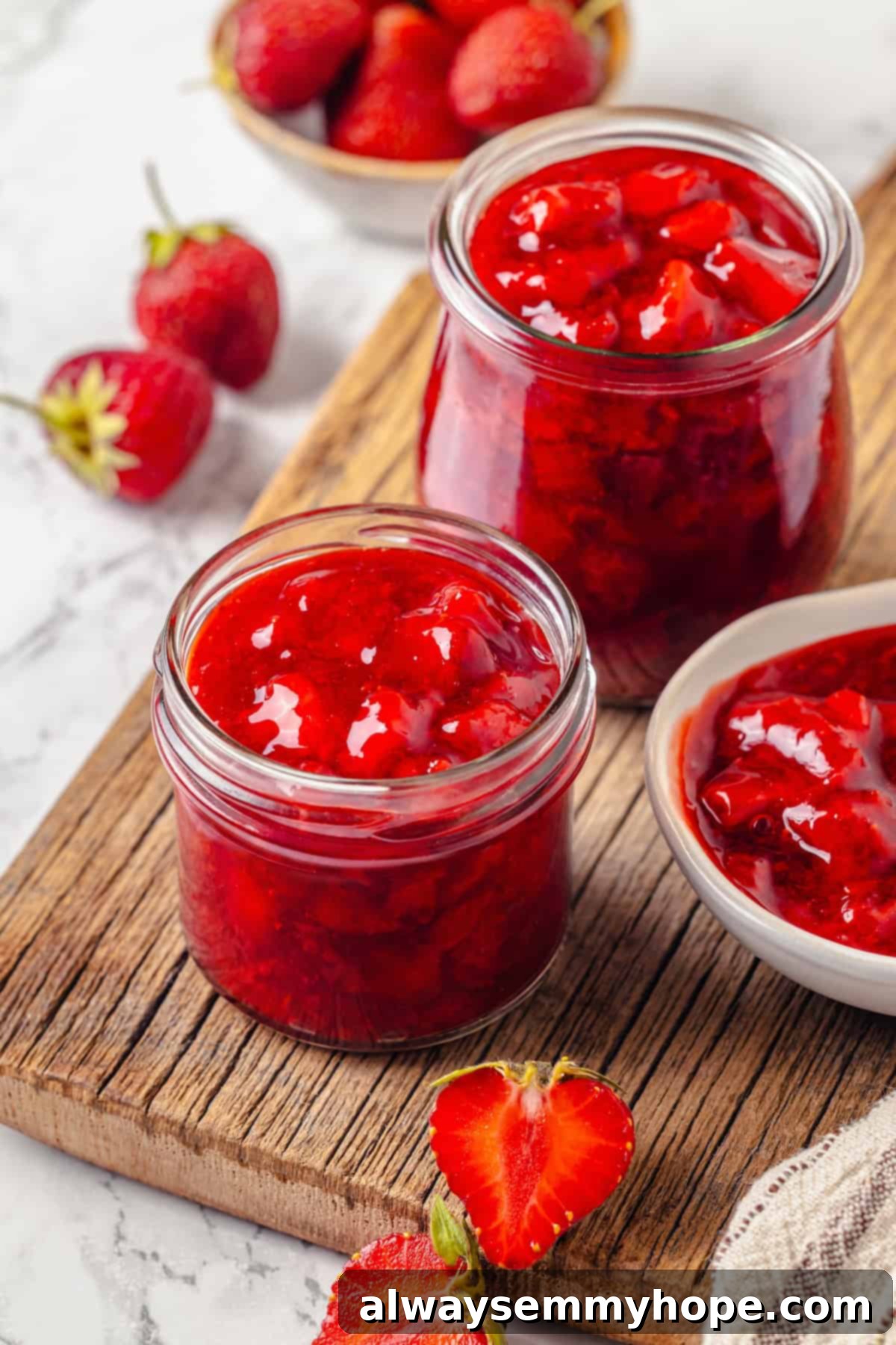 Two jars and a bowl of thick, red strawberry filling, ready for use