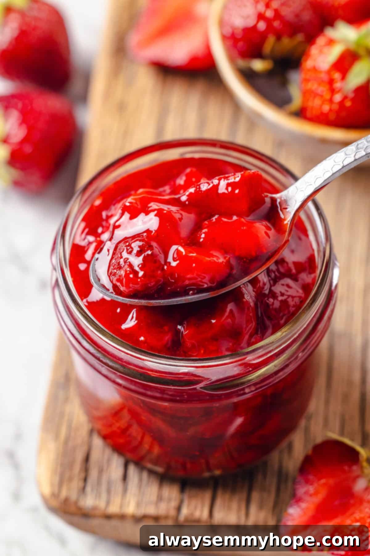 Spoonful of thick strawberry cake filling in a glass jar, showcasing its texture